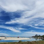 View of Good Harbor Beach with a blue sky, clouds, and horizon