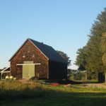 A barn stands at a farm during sunset